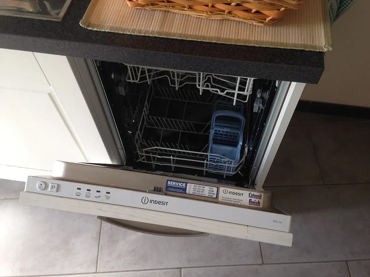 An open dishwasher with racks pulled out and the control panel along the top edge.