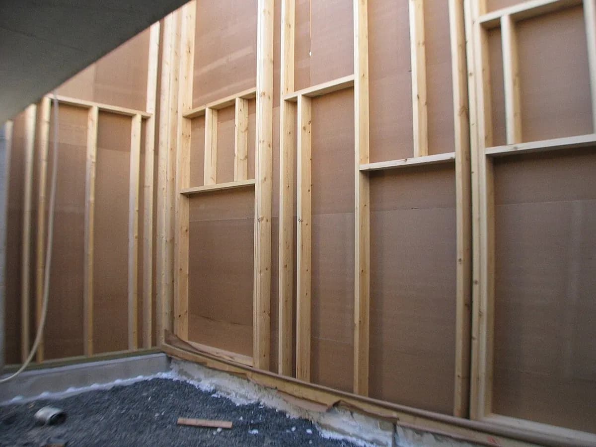 Inside corner of a wall frame with vertical studs and sheathing boards.