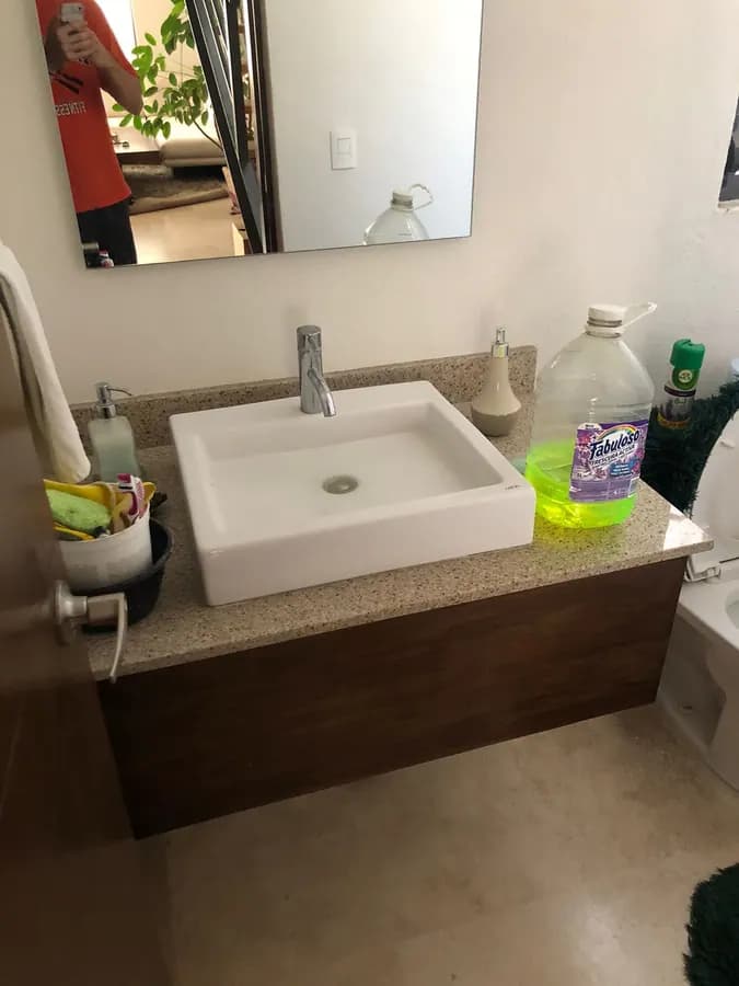 A clean bathroom with a vessel sink and a bottle of green cleaner on the counter.