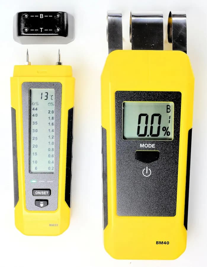 Two yellow handheld moisture meters, one with a bar of lights and one with a digital screen.