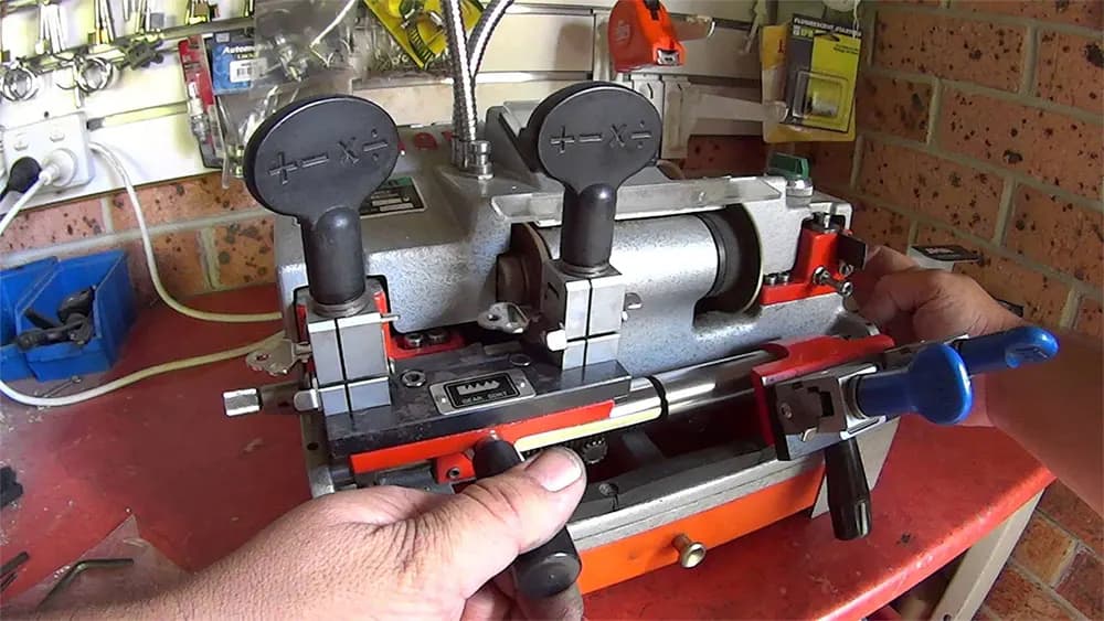 A hand placing a key blank into a key-cutting machine.