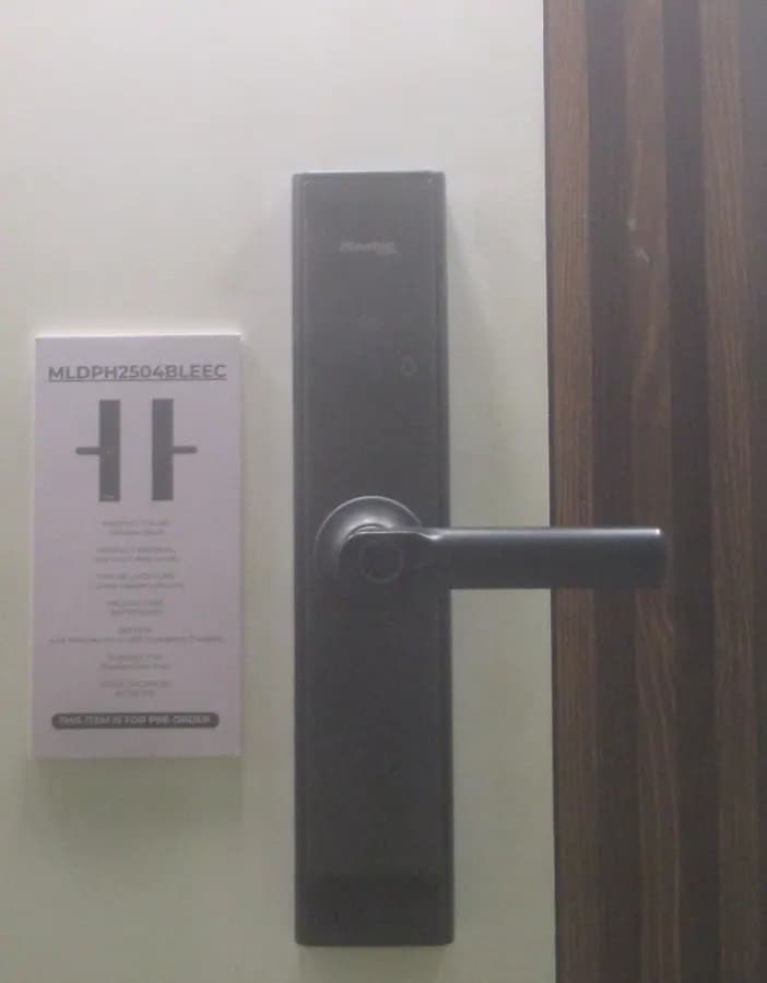 A black smart lock with a lever handle fitted to a wooden door.