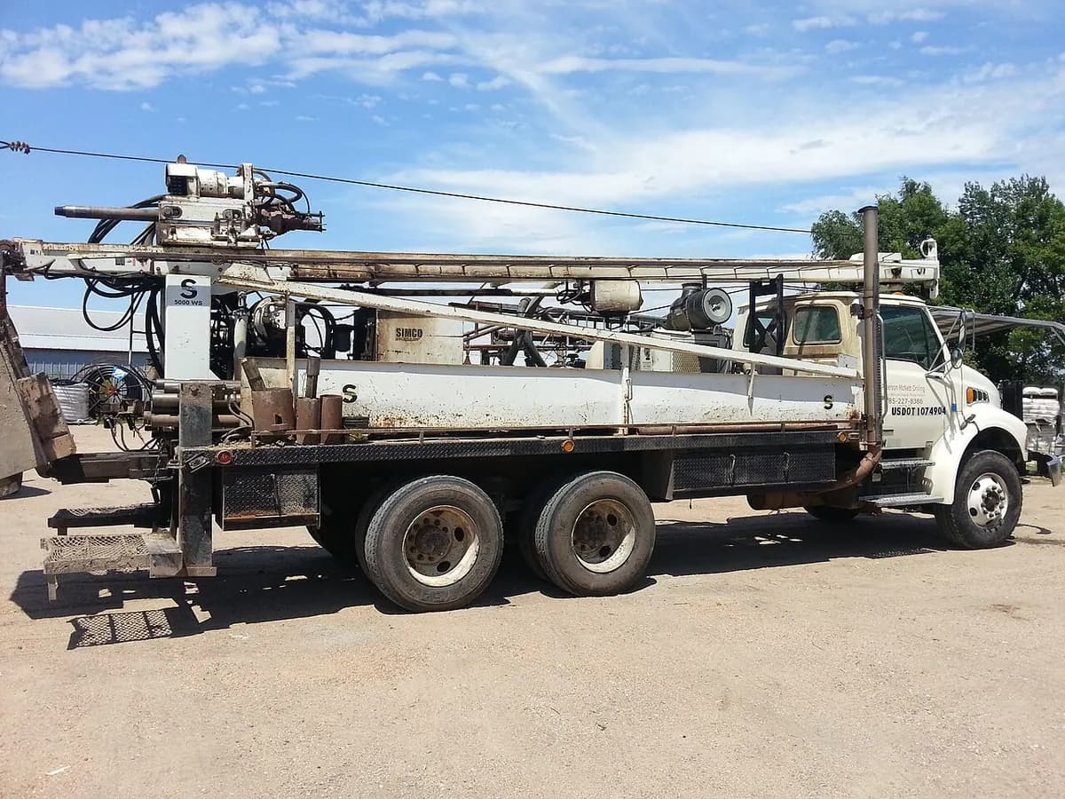 A truck-mounted water well drilling rig with a tall mast.