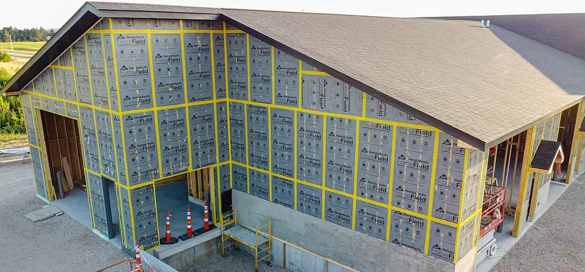 A house frame covered in blue-gray sheathing panels with taped seams.