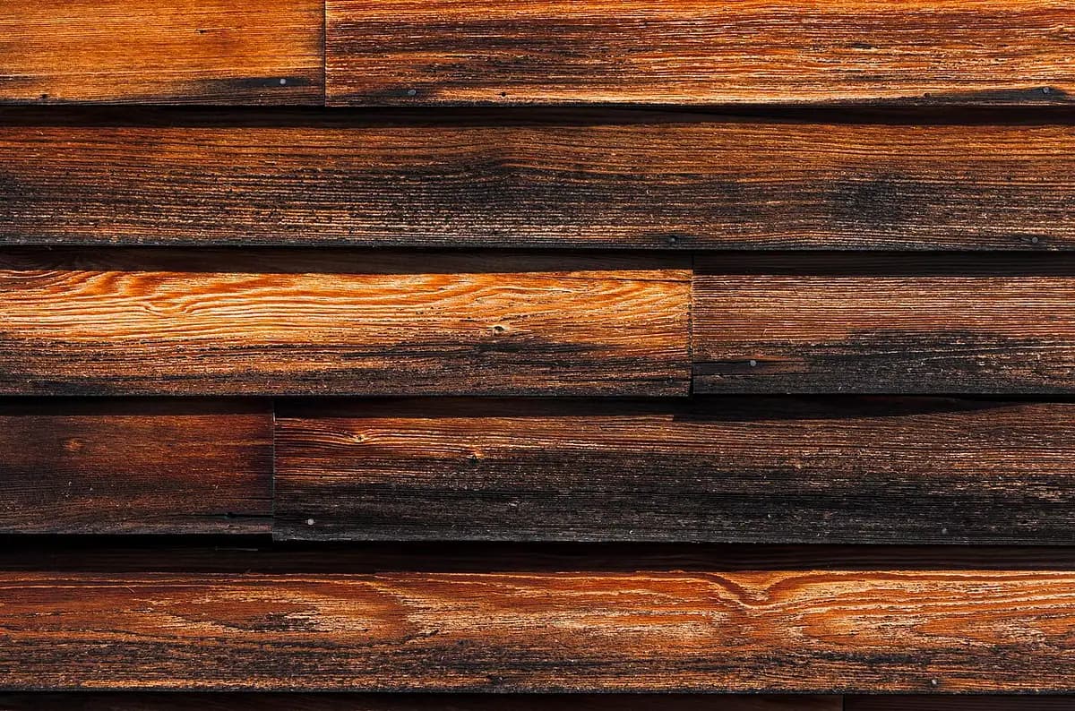 Close-up of weathered, stained wood clapboard siding.