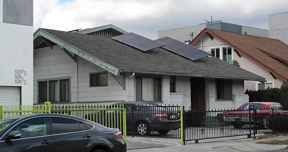 A bungalow seen from the street with solar panels on one roof slope.