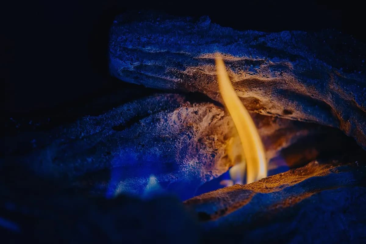 A small gas pilot flame burning in a gas fireplace.
