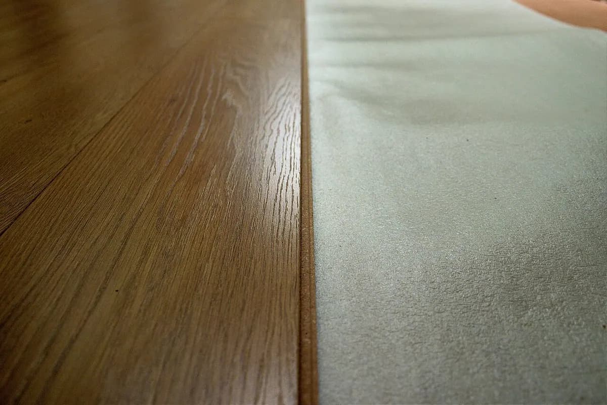 Close-up of a wood-look plank floor meeting the edge of white foam underlayment.