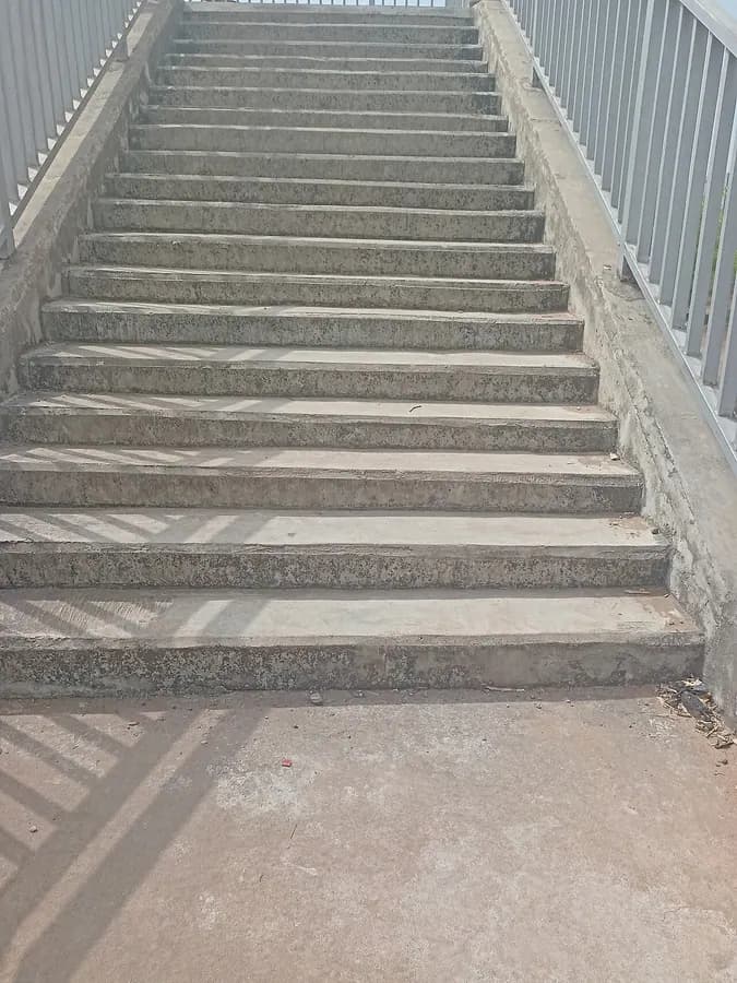 A flight of concrete steps with a metal railing at the side.
