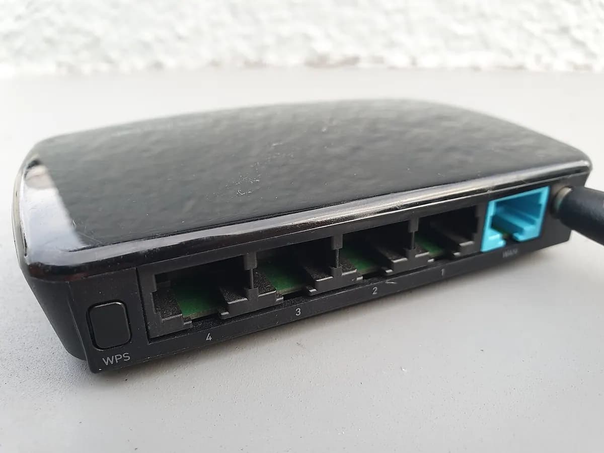 A black Wi-Fi router lying on its side with network ports along the end.