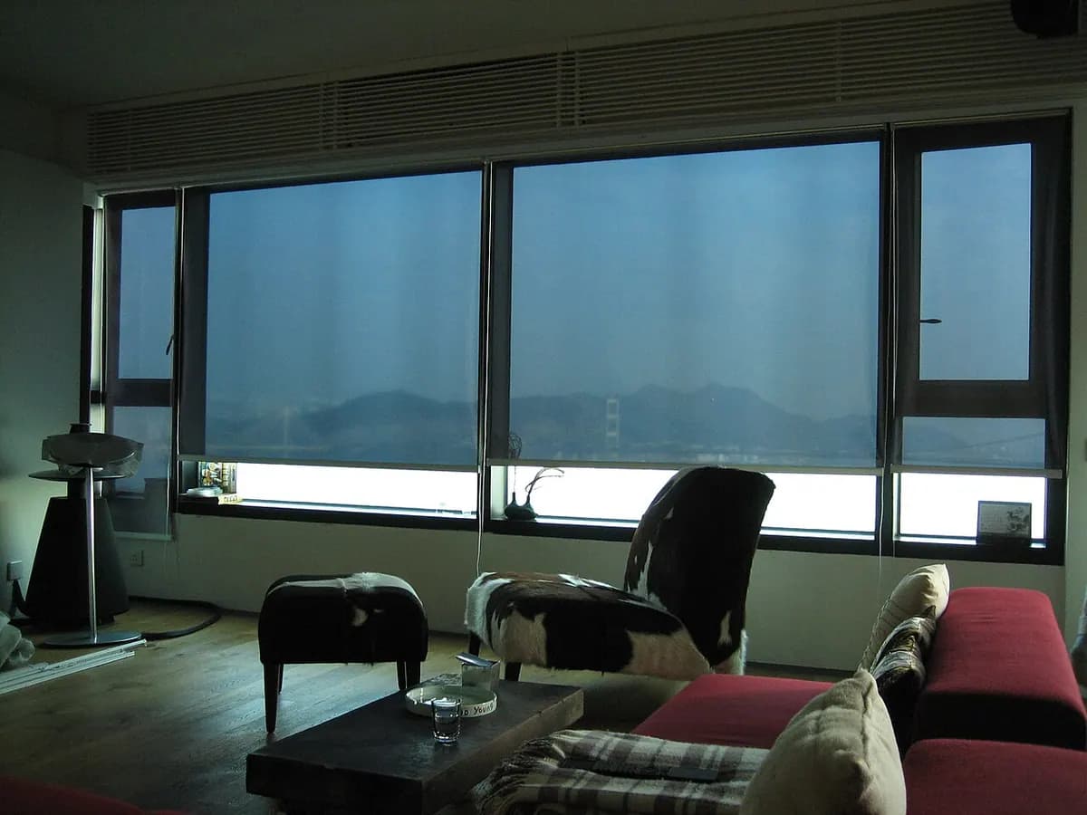 A living room with large windows covered by lowered solar shades.